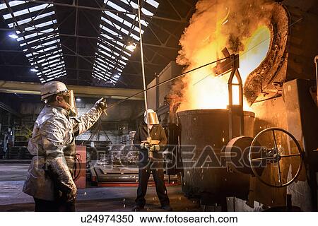 Stock Image - Workers pouring molten metal in factory. Fotosearch