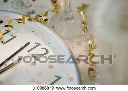 Stock Photo - 12 o'clock on clock decorated with confetti and streamer. Fotosearch