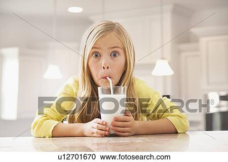 Stock Image - Blonde girl (6-7) drinking milk. Fotosearch