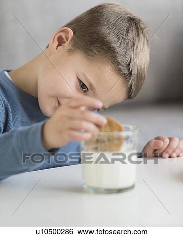 Boy (4-5) dipping cookie in milk View Large Photo Image Stock Photograph - Boy (4-5) dipping cookie in milk. Fotosearch