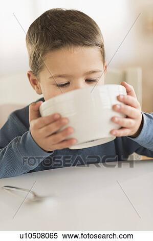 Stock Photography - Boy (4-5) drinking from bowl. Fotosearch
