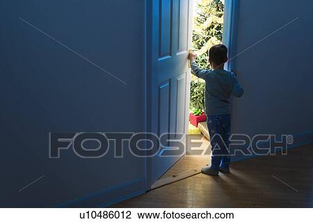 Stock Image - Boy (4-5) peeking through doorway. Fotosearch
