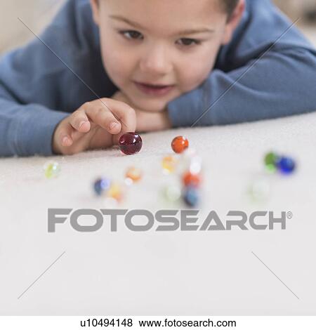 Boy (4-5) playing with marbles View Large Photo Image Stock Photo - Boy (4-5) playing with marbles. Fotosearch