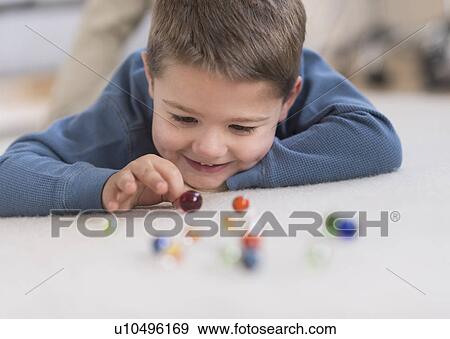 Boy (4-5) playing with marbles View Large Photo Image Stock Photo - Boy (4-5) playing with marbles. Fotosearch