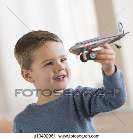 Stock Image - Boy (4-5) playing with toy plane. Fotosearch