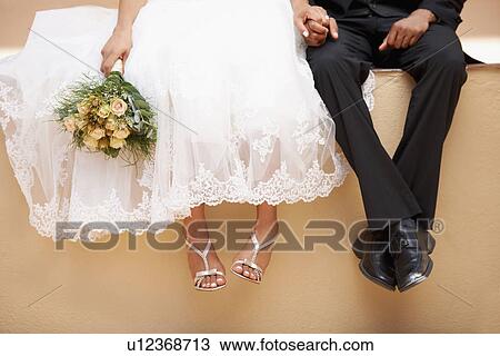 Stock Image - Bride and groom sitting on wall. Fotosearch