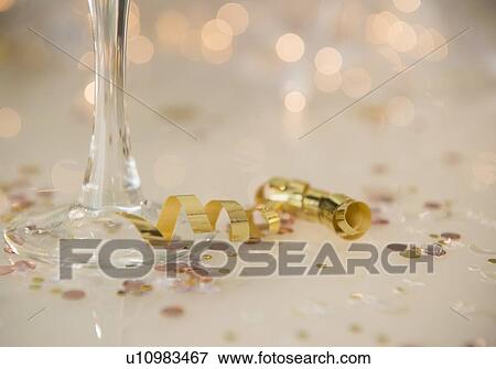 Champagne flute on table decorated with confetti and streamer View Large Photo Image Stock Photo - Champagne flute on table decorated with confetti and streamer. Fotosearch