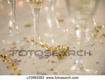 Stock Image - Champagne flutes on table decorated with confetti and streamer. Fotosearch