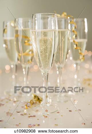 Stock Photo - Champagne flutes on table decorated with confetti and streamer. Fotosearch