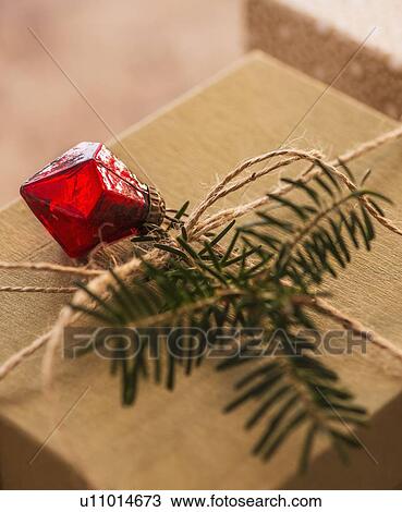 Stock Image - Christmas gift decorated with pine leaf and bauble. Fotosearch