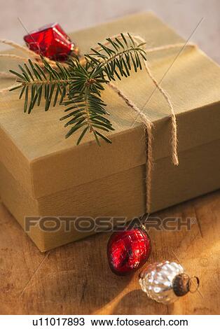 Stock Image - Christmas gift decorated with pine leaf and bauble. Fotosearch