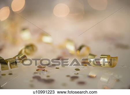 Stock Image - Close-up of gold streamer and confetti. Fotosearch