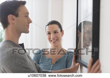 Couple hanging picture on wall View Large Photo Image Stock Photo - Couple hanging picture on wall. Fotosearch