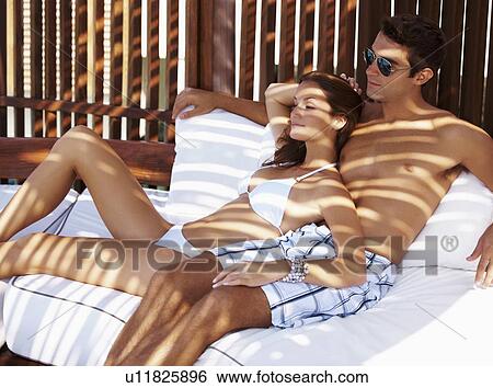 Couple relaxing on chaise lounge View Large Photo Image Stock Photograph - Couple relaxing on chaise lounge. Fotosearch
