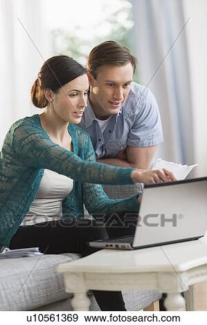 Stock Photo - Couple using laptop together to pay bills. Fotosearch