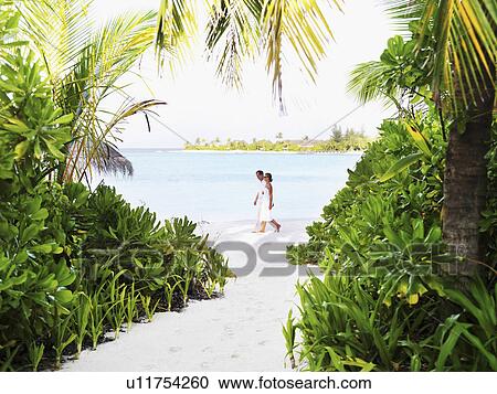 Stock Image - Couple walking at beach. Fotosearch
