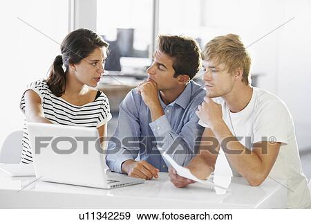 Coworkers discussing at table View Large Photo Image Stock Photo - Coworkers discussing at table. Fotosearch