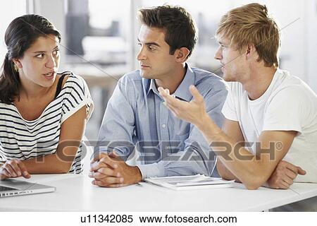 Stock Photography - Coworkers discussing at table . Fotosearch