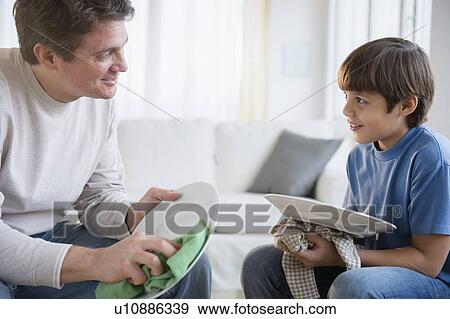 Stock Photo - Father and son (8-9) drying dishes. Fotosearch