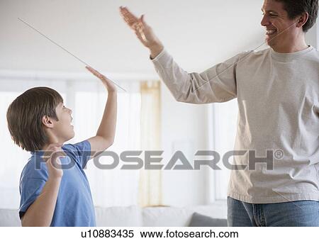 Stock Photography - Father and son (8-9) giving each other high five. Fotosearch