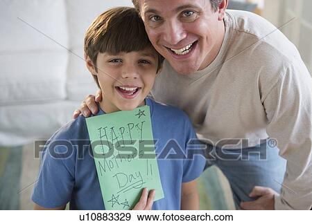 Father and son (8-9) holding Mother's day card View Large Photo Image Stock Photo - Father and son (8-9) holding Mother's day card. Fotosearch