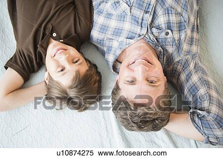Father and son (8-9) lying on bed View Large Photo Image Stock Photography - Father and son (8-9) lying on bed. Fotosearch