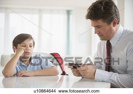 Father and son (8-9) sitting at table View Large Photo Image Picture - Father and son (8-9) sitting at table. Fotosearch