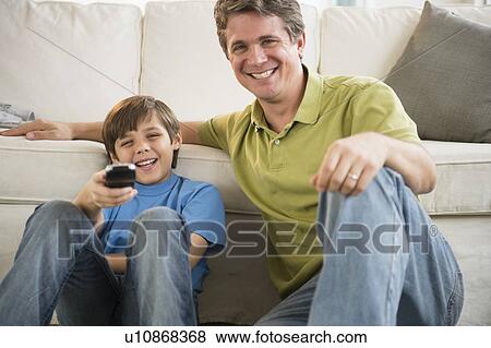 Father and son (8-9) watching television View Large Photo Image Stock Photo - Father and son (8-9) watching television. Fotosearch