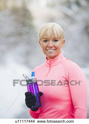 Picture - Female athlete drinking water outdoors. Fotosearch