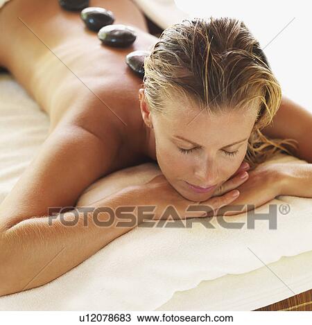 Stock Image - getting hot stone therapy in spa. Fotosearch