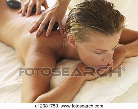 Stock Image - getting hot stone therapy in spa. Fotosearch