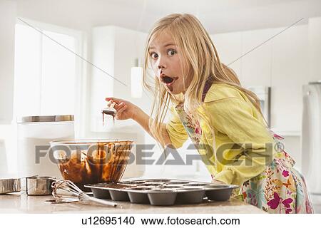 Stock Image - Girl (6-7) baking cupcakes. Fotosearch