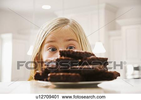 Girl (6-7) looking at heap of brownies View Large Photo Image Stock Image - Girl (6-7) looking at heap of brownies. Fotosearch
