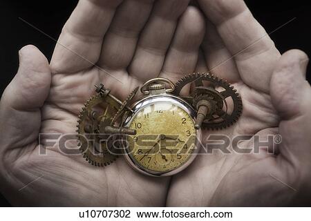 Stock Image - Hands holding antique clock and gears. Fotosearch