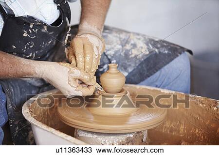 Stock Image - Hands working with clay on potter's wheel. Fotosearch