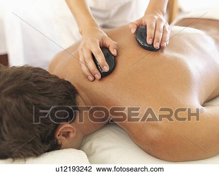 Stock Image - Man getting stone massage in spa. Fotosearch