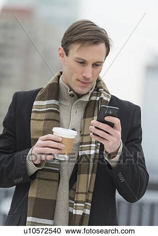 Man in winter clothes looking at phone View Large Photo Image Stock Image - Man in winter clothes looking at phone. Fotosearch