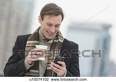 Man in winter clothes looking at phone View Large Photo Image Stock Image - Man in winter clothes looking at phone. Fotosearch