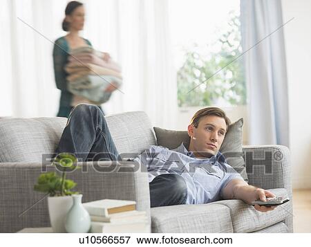 Man lying on sofa watching tv View Large Photo Image Stock Photo - Man lying on sofa watching tv. Fotosearch