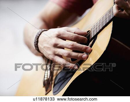 Stock Image - Man playing guitar, close-up. Fotosearch
