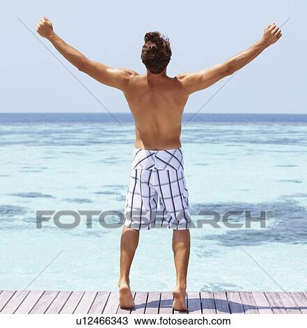 Stock Image - Man standing on swimming pool jetty. Fotosearch
