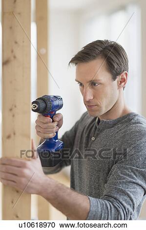 Stock Image - Man using hand drill. Fotosearch