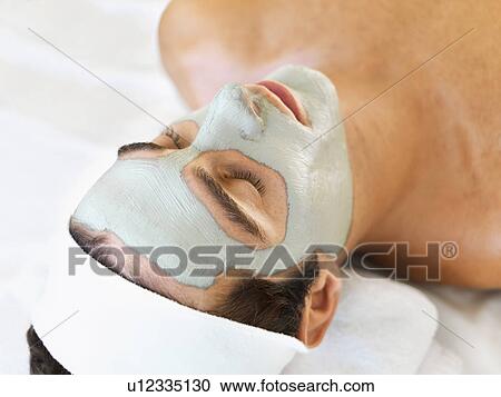 Stock Image - Man with face mask relaxing in spa. Fotosearch