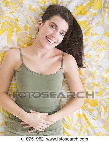 Stock Image - Portrait of beautiful woman lying on bed. Fotosearch