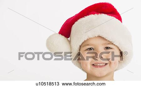 Stock Image - Portrait of boy (4-5) wearing santa hat. Fotosearch