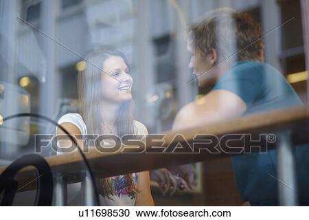 Stock Image - Portrait of couple talking in coffee shop. Fotosearch