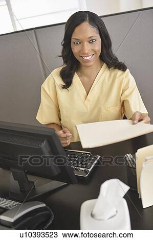 Stock Image - Portrait of female nurse at station. Fotosearch