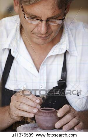 Portrait of male potter carving small vase View Large Photo Image Stock Photo - Portrait of male potter carving small vase. Fotosearch