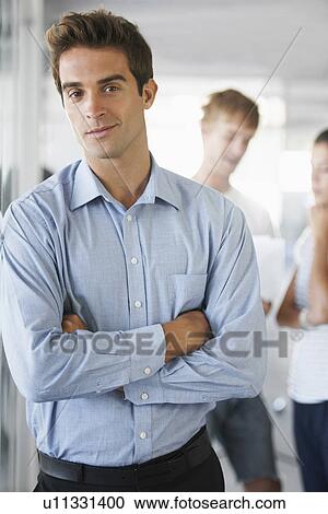 Stock Image - Portrait of man with coworkers in background. Fotosearch