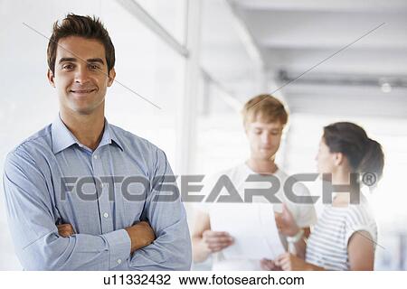 Stock Image - Portrait of man with coworkers in background. Fotosearch